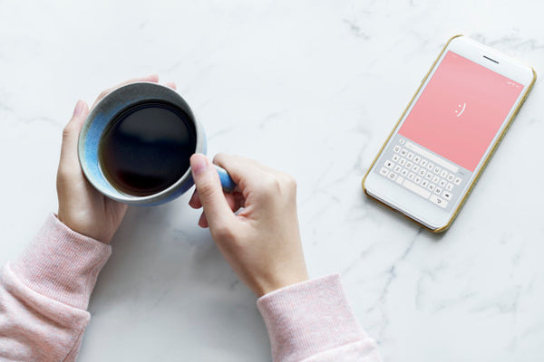 Free Aerial View Of Woman With A Hot Cup Of Coffee And A Smartphone Psd