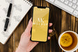 Free Flat Lay Hand Holding Smartphone Mock-Up With Tea On Desk Psd