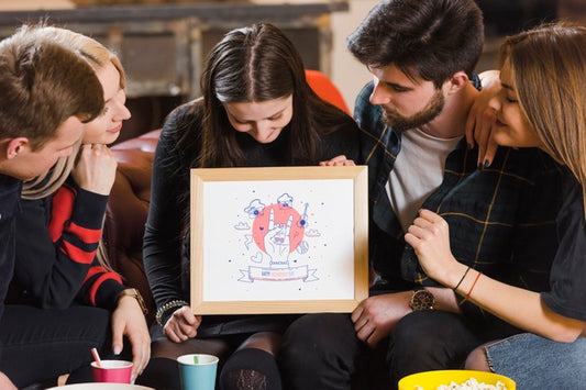 Free Friends Looking At A Frame Mock-Up While Holding It Psd