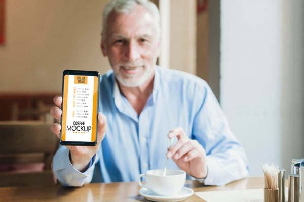 Free Front View Man In Coffee Shop Holding Mobile Mock-Up Psd