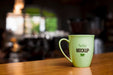 Free Green Coffee Cup On Wooden Table Psd