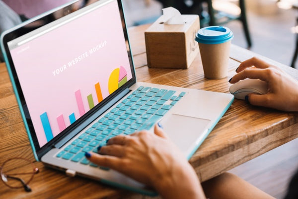 Free Laptop Mockup With Woman On Wooden Table Psd