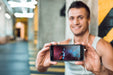 Free Man In Gym Holding Smartphone Mockup Psd