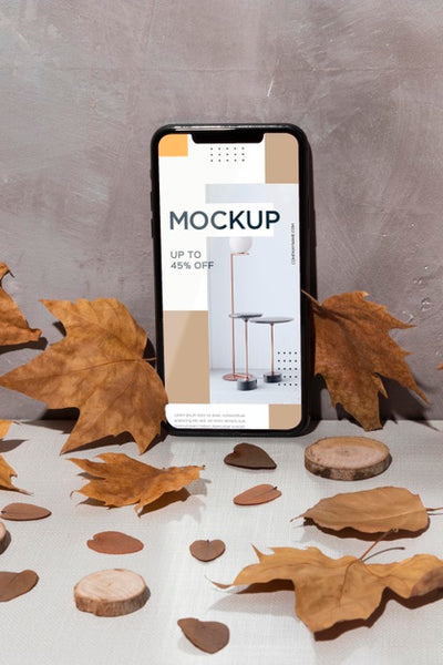 Free Mobile Phone Mockup Standing On The Table Surrounded By Leaves Psd