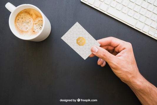 Free Mock Up Of Hand Holding Business Card With Coffe And Keyboard Psd