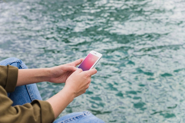 Free Person Using Smartphone Mockup On Sea Background Psd