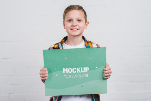 Free Portrait Of Smiley Kid Holding Mock-Up Sign Psd