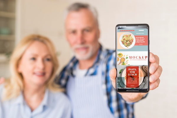 Free Senior Couple In Kitchen Holding Smartphone Mock-Up Psd