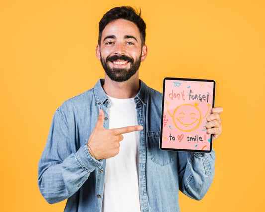 Free Smiling Young Man Pointing Finger At Tablet Mock Up Psd
