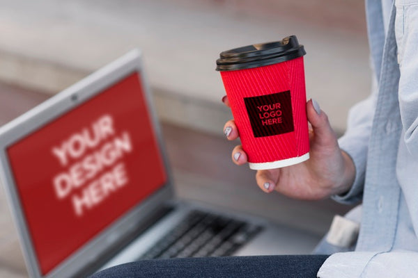 Free Woman Holding A Cup Of Coffee While Sitting Next To A Laptop Mock-Up Psd