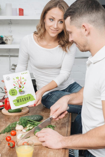 Free Woman Holding Book In The Kitchen While Man Cooks Psd
